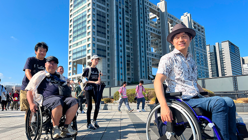 都市部で車いすユーザーを含むグループが街歩き研修を行う様子