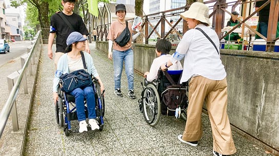 車いすユーザーを含むグループが橋の上で街歩き調査をする様子