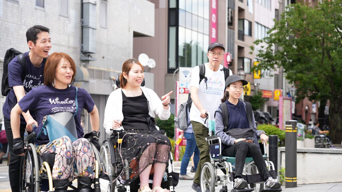 WheeLogのシャツを着た調査メンバーが街中でバリアフリー調査をする様子